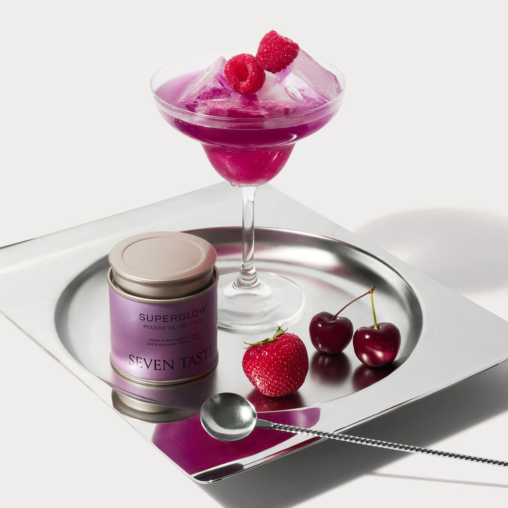 Mocktail violet aux fruits rouges préparé avec la poudre Superglow Seven Taste, servi en coupe avec framboises et glaçons.