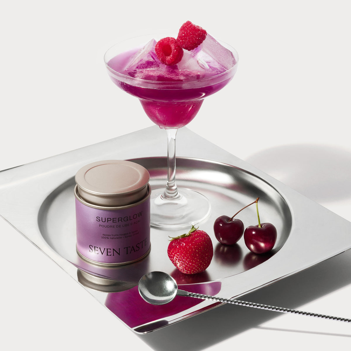 Mocktail violet aux fruits rouges préparé avec la poudre Superglow Seven Taste, servi en coupe avec framboises et glaçons.
