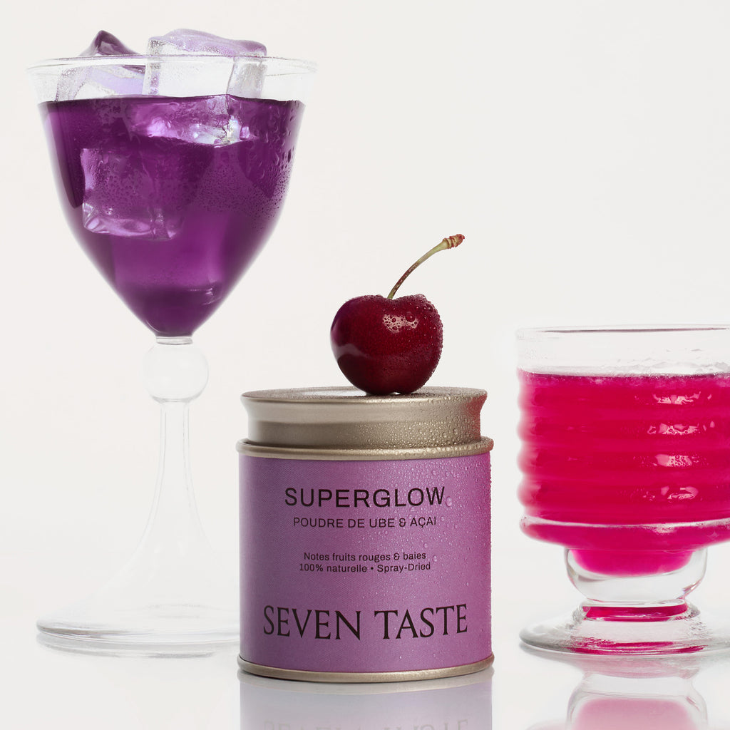 Deux mocktails préparés avec Superglow Seven Taste, teintes violet et rose, avec une cerise fraîche posée sur la boîte.
