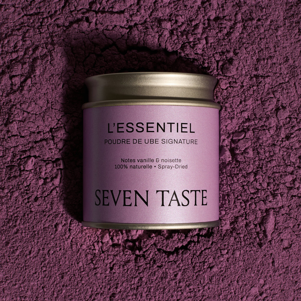 Boîte de poudre de ube signature Seven Taste « L’Essentiel » sur fond de poudre de ube violette, superaliment naturel aux notes de vanille et noisette.